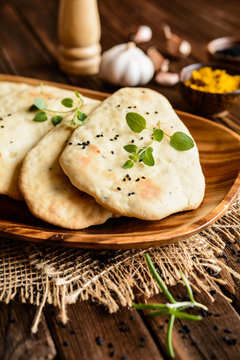 Traditional Indian Naan bread with garlic on a wooden background
