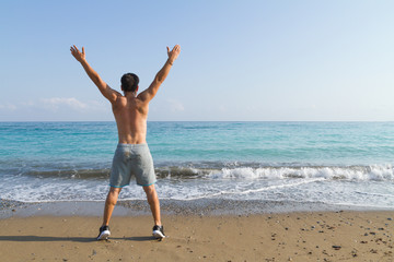 Fototapeta na wymiar Young man doing streching fitness training at the beach