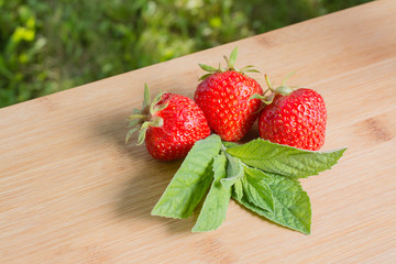 Ягоды клубники и листья мяты на деревянном столе