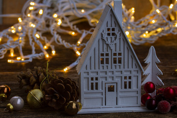 White wooden christmas house with cones glowing with lights in background