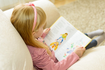 Девочка читает, сидя в кресле