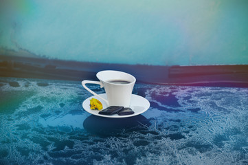 Cup of coffee on a frozen blue car