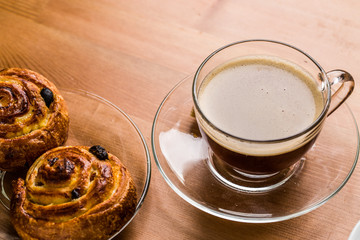 Coffee cup with cinnabon on wooden background.