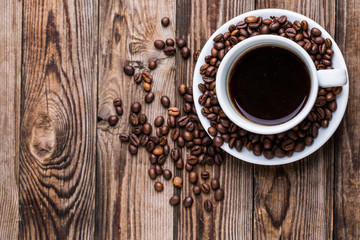 Coffee cup and coffee beans on wooden background.
