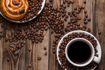 Coffee cup with coffee bean and cinnabons on wooden background.