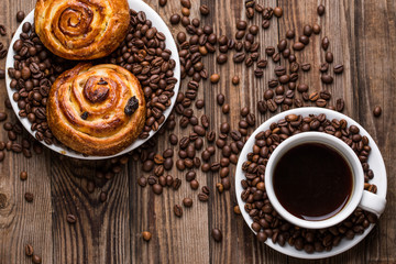Coffee cup with coffee bean and cinnabons on wooden background.
