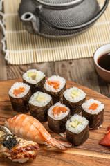 Rolls with avocado and tuna, assorted sushi on wooden plate