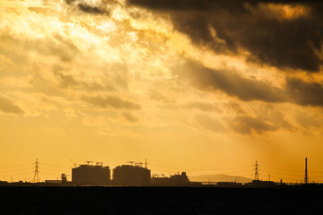 Power plant factory silhouette over sunset at sea