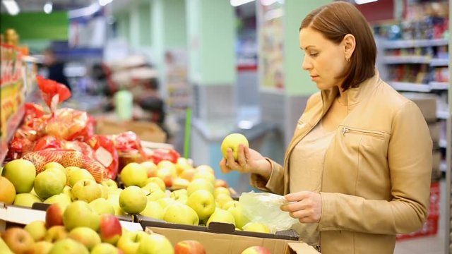 woman buys apples at the supermarket