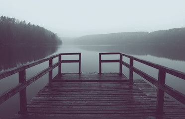 Colorized picture of old wooden pier on foggy lake in the morning