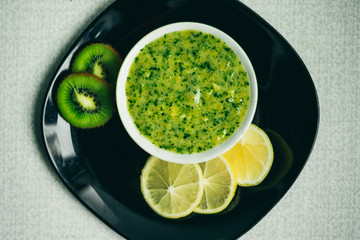 green smoothie with lemon and kiwi fruit on black plate