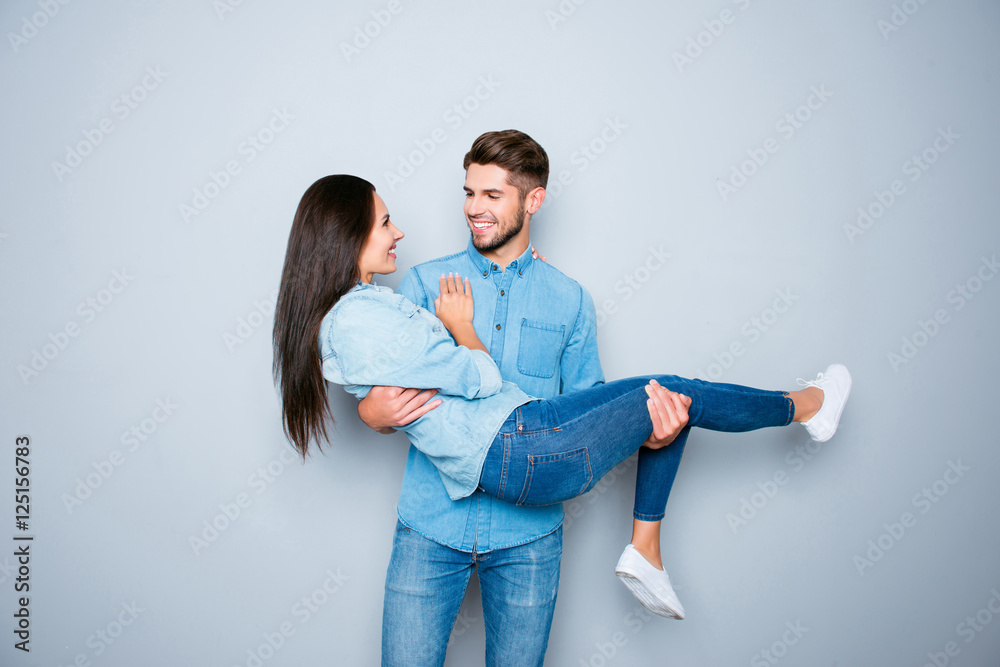 Wall mural happy smiling young man carrying his pretty girlfriend - Wall murals
