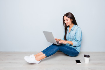 Young smiling woman working on laptop while sitting on floor