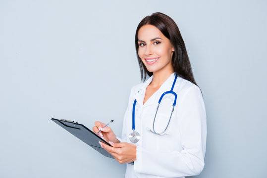 Attractive female doctor with folder writing diagnosis