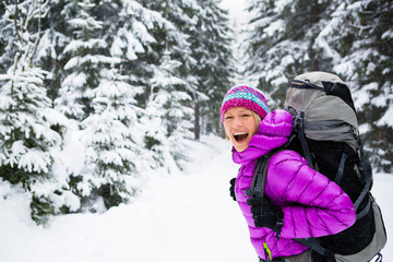 Fototapeta na wymiar Happy woman walking in winter forest with backpack