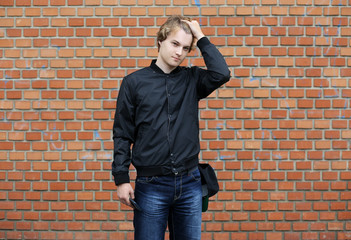 Portrait of attractive teenage boy standing  in front of a brick wall.