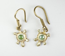 Fototapeta na wymiar Two gold earrings shaped as turtle with green stone shell
