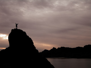 Man on mountain with arms raised in Victory