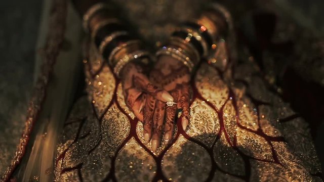 Shadows lie over the knees of Hindu bride dressed in golden clothes
