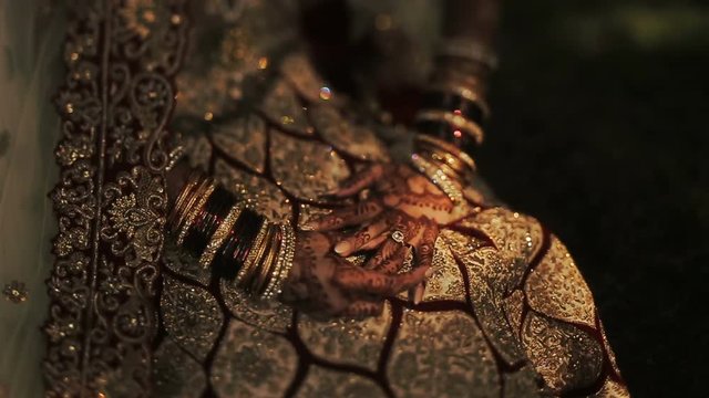 Shadows lie over the knees of Hindu bride dressed in golden clothes