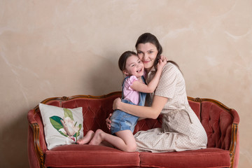 Mother and daughter embrace on the red sofa