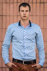 Cool fashion man in blue shirt standing and looking away.