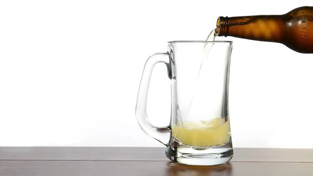 Fresh, cold, crisp beer being poured into a classic pint mug against a white background.