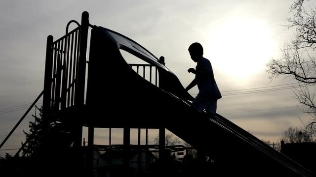 Abstract outline of kids playing at playground with the sun in the background covered by clouds.