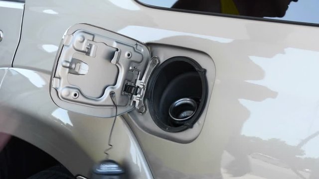 A man pops his gas tank cover, removes the cap and fills his car with gasoline. Clip was designed to provide users with the option to crop for a beginning fill or for an end of fill, or retain both..