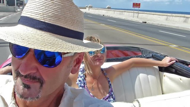 Happy, caucasian couple driving in a cabriolet.Drive trough Havana city, Cuba.