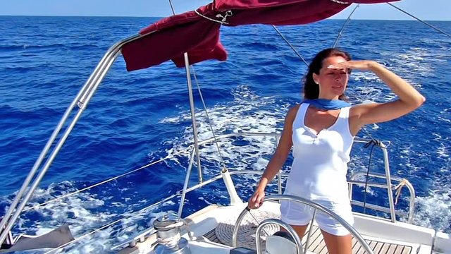Beautiful lady skipper navigating a sailboat.Slow motion, high speed camera