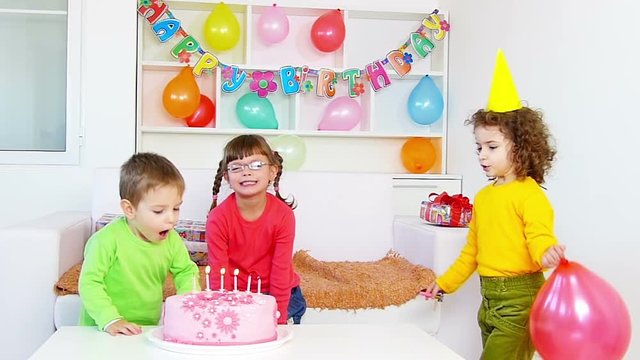 Children Blowing Out Candles on a Birthday Cake.Slow motion, high speed camera