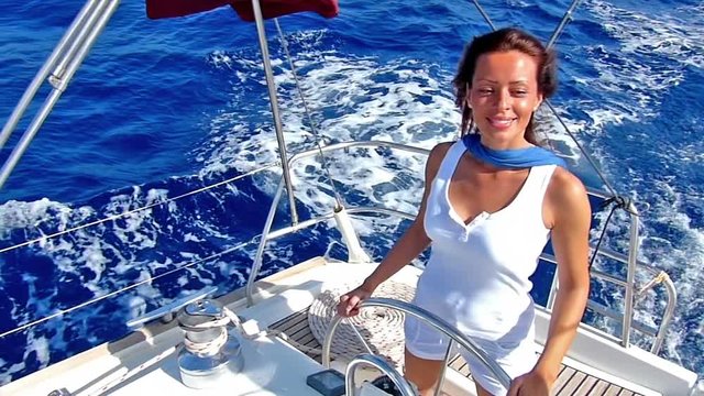 Beautiful lady skipper navigating a sailboat.Slow motion, high speed camera