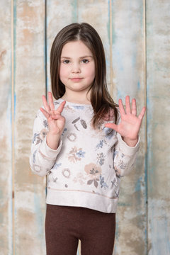 little girl in sweater showing nine fingers 
