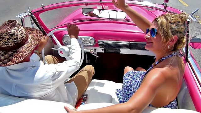 HAVANA,CUBA 2014, October 09 : Happy, caucasian woman greeting from a cabriolet.Drive through Havana city, Cuba.Slow motion, high speed camera