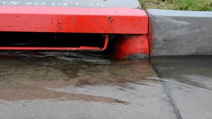 Rain creates water runoff along the side of a street, which drains into a city sewer system that leads to the ocean. Video is looped for unlimited duration. .