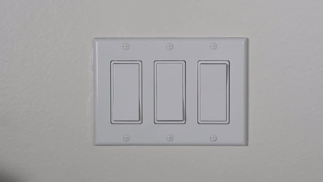 A man turns on a hallway light then a main living room light, bringing darkness to light..