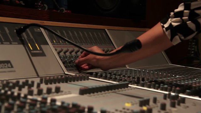 Recording studio music mixing desk console with engineer hand turning nob