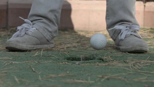 SLOW MOTION: Little player legs and a golf ball runs to hole