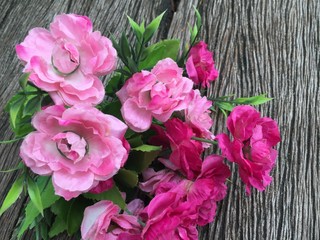 Pink artificial flower bouquet on wood background