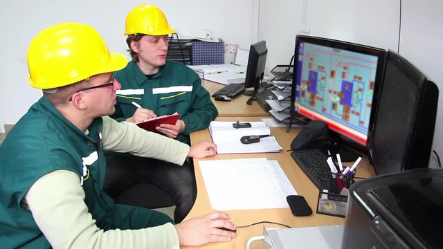 Industrial workers in a control room,working with computers and controls the operation of devices in a power plant