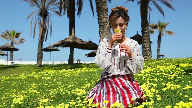 Young woman smells a yellow flowers in a beautiful garden