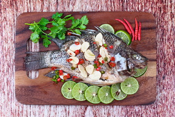 Tilapia fish streamed with lemon topped spicy sour ginger and chili on butcher served. (Call Pla Nil Nuang Manoaw in Thai) isolated white background.