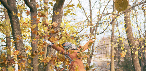 Happy woman playing with leaves in the park