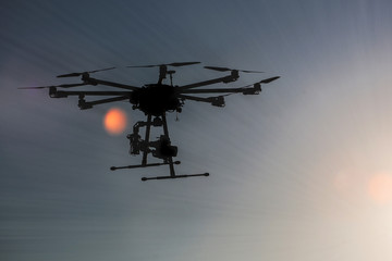 Fototapeta na wymiar Professional drone flying in the sunset, Octocopter, copter, drone 