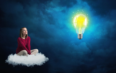 Woman sitting on a cloud lokking at huge lightbulb