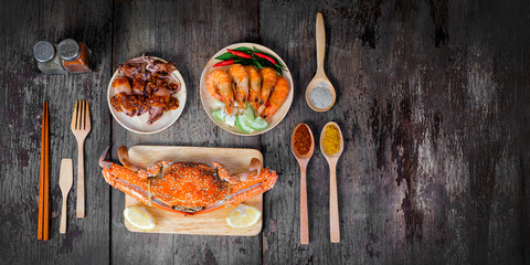 Delicious grilled seafood (jumbo crabs, prawns,  squids) with spices on wood table
