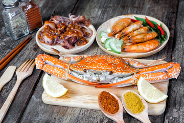 Delicious grilled seafood (jumbo crabs, prawns,  squids) with spices on wood table