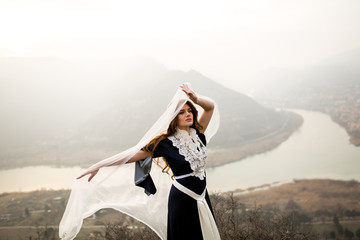 beautiful girl in dress on the rocks (behind the mountains and the river)