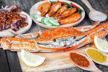 Delicious grilled seafood (jumbo crabs, prawns,  squids) with spices on wood table